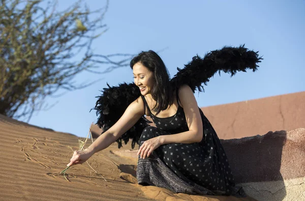 Mulher chinesa com asas negras em um deserto — Fotografia de Stock