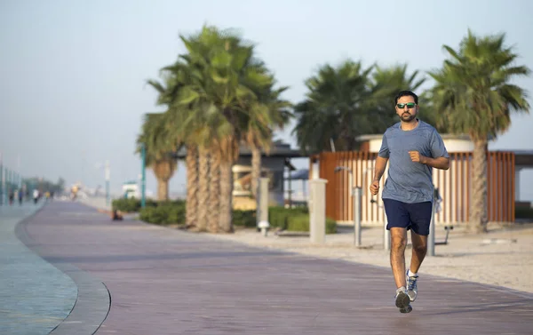man running on a running track near beach