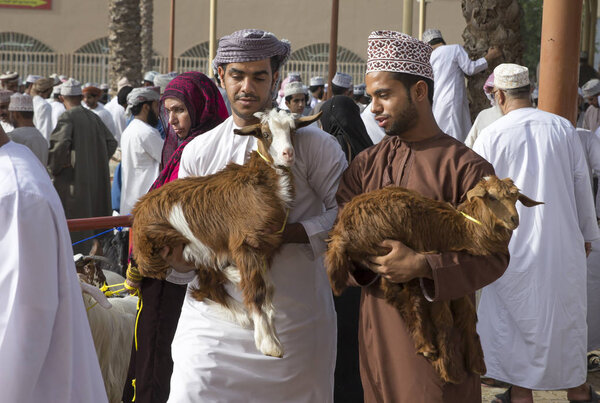 omani men carrying goats 