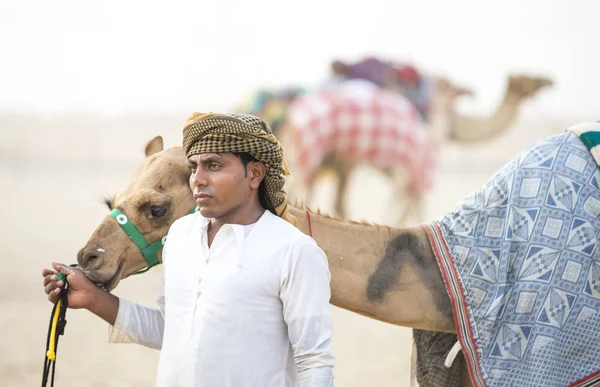 L'uomo con il suo cammello su una pista di cammello in un deserto — Foto Stock