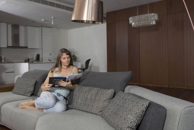 Kadın evde kitap okuyor.