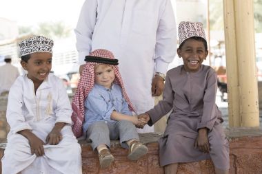 Nizwa, Umman, 10 Kasım 2017: omani çocuk ve Avrupa çocuk parapetin üzerinde otururken el sıkışan