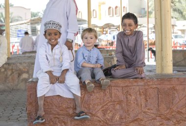 Nizwa, Umman, 10 Kasım 2017: omani çocuk ve Avrupa çocuk parapetin üzerinde oturan