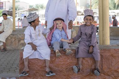 Nizwa, Umman, 10 Kasım 2017: omani çocuk ile el sıkışan ve gülümseyen beyaz çocuk