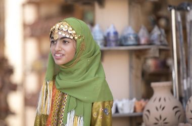 Nizwa, Umman, 10 Kasım 2017: geleneksel cloting Dükkanı arka plan gülümseyen omani kız