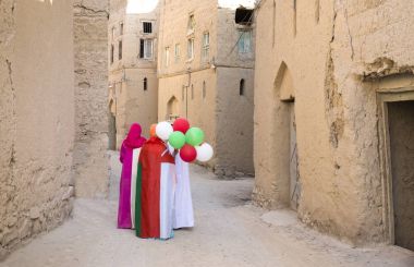 omani ladies wearing omani flags and baloons with national colors clipart