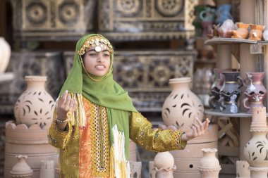 Nizwa, Umman, 10 Kasım 2017: Hatıra Eşyası Dükkanı sunan geleneksel kılığına girmiş omani kız