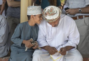 Nizwa, Umman, 10 Kasım 2017: tespih dokunmaktan ve oğlu ile konuşurken omani adam