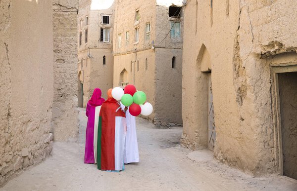 omani ladies wearing omani flags and baloons with national colors