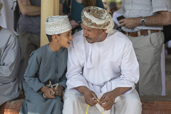 Nizwa, Oman, 10th November 2017: omani man touching rosary beads and talking with son