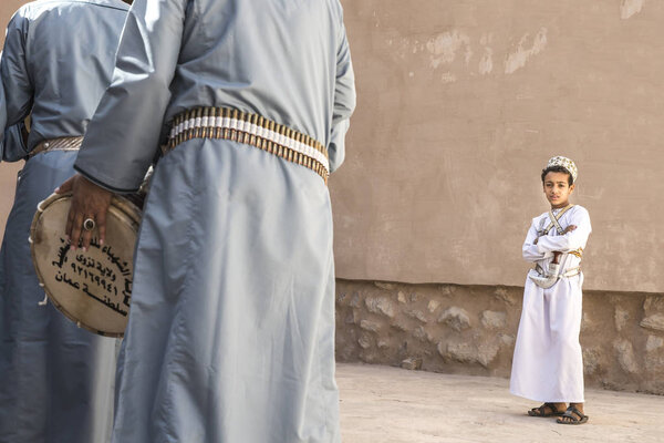 Nizwa, Oman, December 1st, 2017: omani boy looking at men celebrating a national day