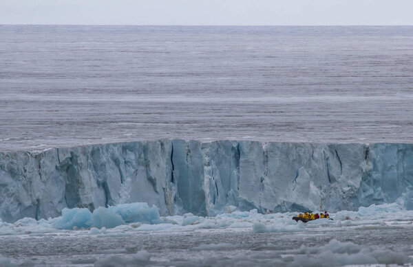 люди путешествуют в зодиаке между айсбергами Шпицбергена

