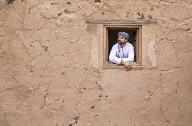 arab man in traditional omani outfit in an old castle clipart