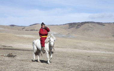 Hatgal, Moğolistan, 3 Mart 2018: Moğol adam bir bozkır Kuzey Moğolistan içinde beyaz atlı