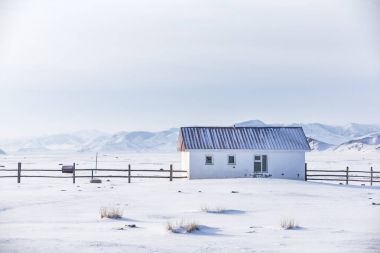 small white house in a snow covered valley in the middle of mountains of Northern Mongolia clipart