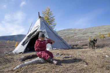 tsaatan çocuk, giyinmiş ev yapımı yay ve oku Tayga Kuzey Moğolistan ile geleneksel bir deel içinde