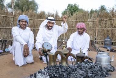 Al Ain, Birleşik Arap Emirlikleri, 16 Kasım 2019: Emirati adamları bir dalleh içinde servis edilen Qahwa adı verilen geleneksel Arap kahvesi hazırlıyorlar.