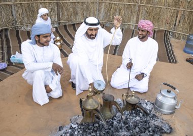 Al Ain, Birleşik Arap Emirlikleri, 16 Kasım 2019: Emirati adamları bir dalleh içinde servis edilen Qahwa adı verilen geleneksel Arap kahvesi hazırlıyorlar.