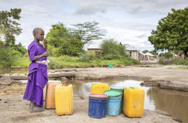 Aynı şekilde, Tanzanya, 11 Haziran 2019: Çamurlu derede içme suyu toplamak için maasai kızı