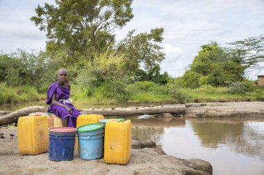 Aynı şekilde, Tanzanya, 11 Haziran 2019: Çamurlu derede içme suyu toplamak için maasai kızı
