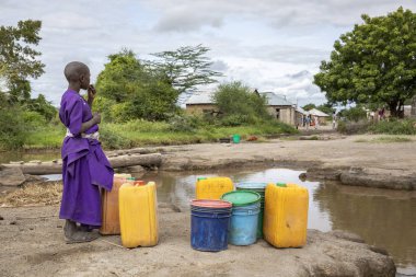 Aynı şekilde, Tanzanya, 11 Haziran 2019: Çamurlu derede içme suyu toplamak için maasai kızı