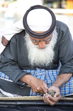 Abu Dabi, Birleşik Arap Emirlikleri, 14 Aralık 2019: Yeni yakalanan istiridyelerde inci arayan yaşlı balıkçı