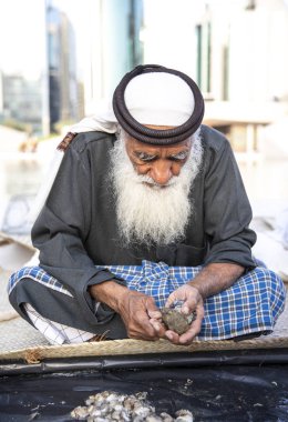 Abu Dabi, Birleşik Arap Emirlikleri, 14 Aralık 2019: Yeni yakalanan istiridyelerde inci arayan yaşlı balıkçı
