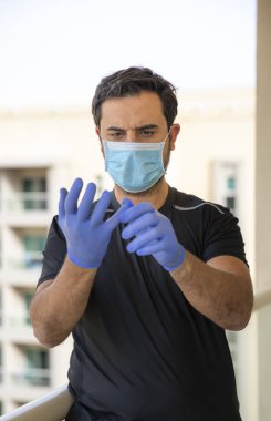 Tıbbi maskeli olgun bir adamın portresi balkonunda, kendini izole etme ve karantina konseptinde