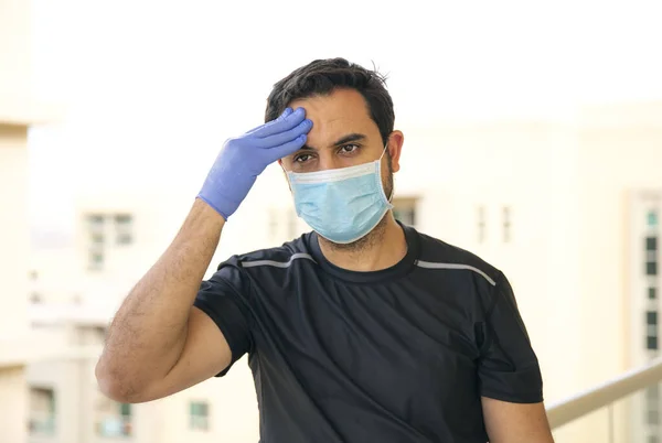 portrait of mature man in medical mask on his balcony, self isolation and quarantine concept