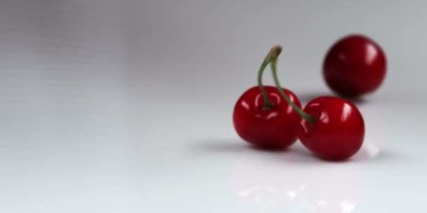 Красные вишни падают на стол — стоковое видео