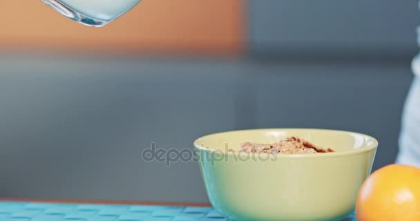 Donna mangiare sana colazione cereali con latte e bere succo d'arancia filmato in risoluzione 4k dci al rallentatore bella donna caucasica mangiare e sorridere al mattino in una cucina accogliente — Video Stock