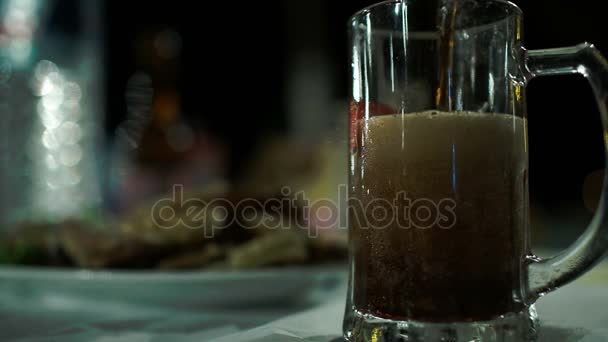 Close-up shot van gieten donker bier met een heleboel schuim in grote glazen mok — Stockvideo