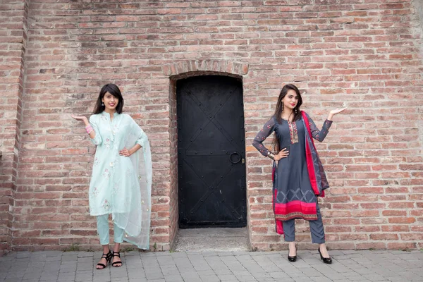 インドの伝統的なドレスを着た2人の女の子が家の入り口に立っている 手を握っている女の子は歓迎ジェスチャーで育ちました — ストック写真