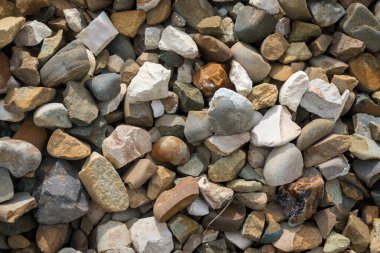 Farklı renklerde taşlarla donatılmış bir arka plan. İnşaat için taş. Bina taşları. İnşaat malzemesi. Çeşitli çakıl taşı dokuları. Kaya dokusu arkaplanı. 