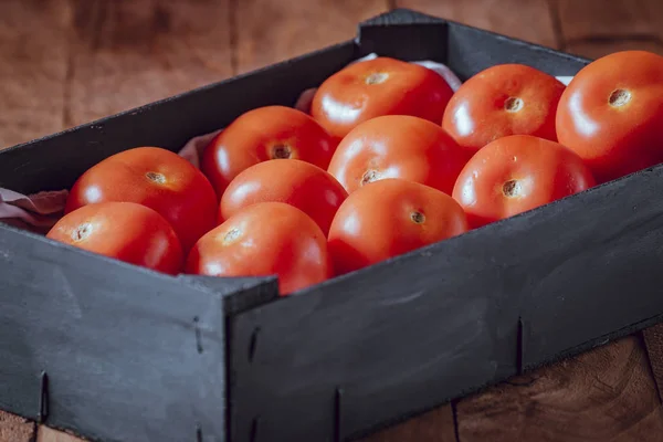 Schwarze Holzkiste mit roten Tomaten der Sorte Roma. — Stockfoto