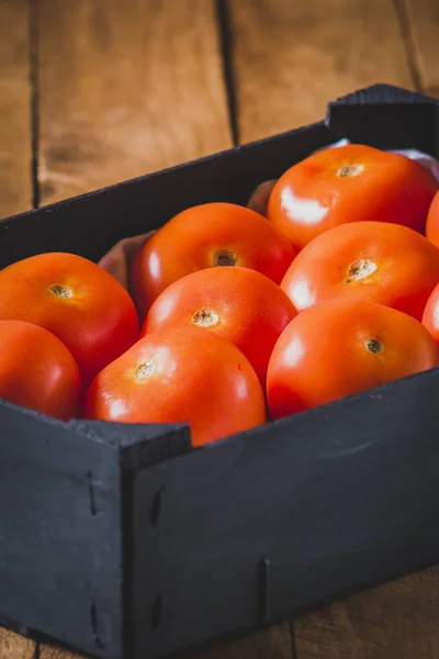 Schwarze Holzkiste mit roten Tomaten der Sorte Roma. — Stockfoto