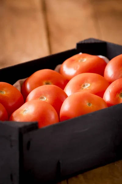 Schwarze Holzkiste mit roten Tomaten der Sorte Roma. — Stockfoto