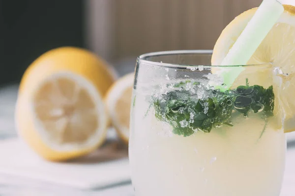 Close-up of a glass of lemonade with aromatic herbs with the lemons cut from the bottom — Stock Photo, Image