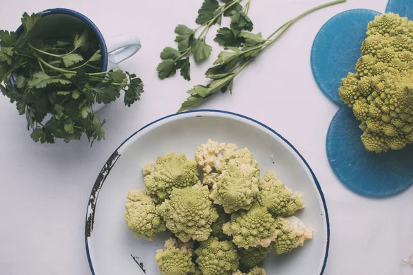 Brócoli de la variedad Romanescu, sobre un plato de hojalata con borde azul sobre fondo blanco . — Foto de Stock