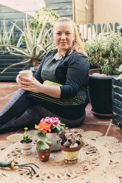 Home gardening concept. Woman resting with a cup after gardening.