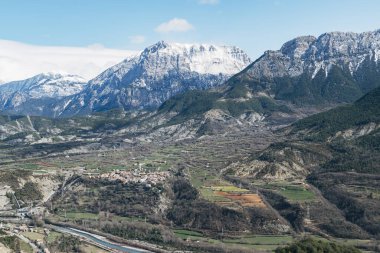 Manzara, arka planında orman olan karlı dağlardan oluşuyordu..