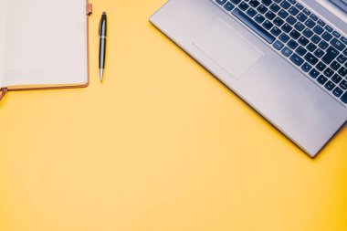 Evden çalışıyorum. Dizüstü bilgisayarı olan bir çalışma masası ve sarı arka planlı bir gündem..