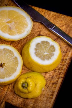 Eski bir kesme tahtasının üzerinde dilimlenmiş taze limonlar..