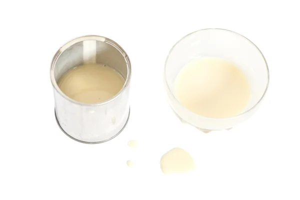 Lait condensé avec sucre dans un bol en verre et une boîte de conserve — Photo