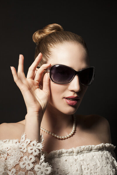 Portrait of Beautiful young woman in sunglasses on black backgro