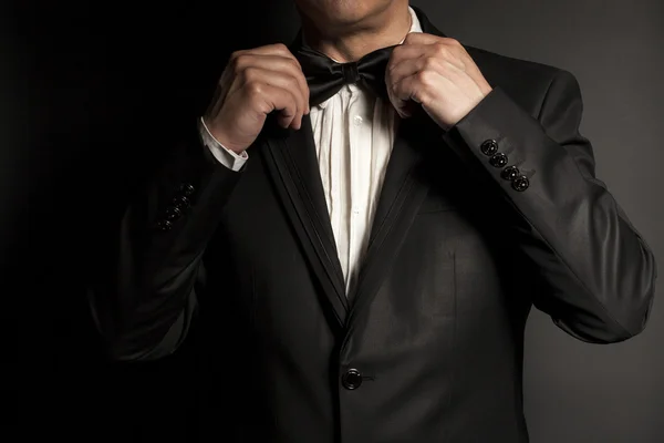 Gros plan de gentleman portant cravate noire redresse son noeud papillon . — Photo