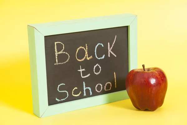 Powrót do szkoły napisany na tablicy i czerwone jabłko — Zdjęcie stockowe