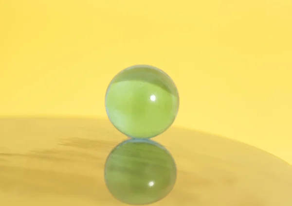 Bola de vidro no fundo amarelo — Fotografia de Stock