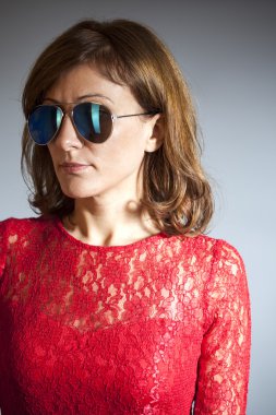 Kırmızı elbise ve güneş gözlüğü gri arka plan üzerinde kadın portresi