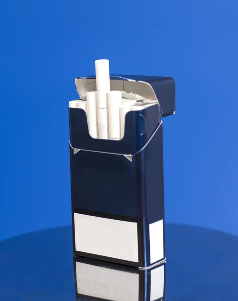 Krabička cigaret na modrém pozadí — Stock fotografie